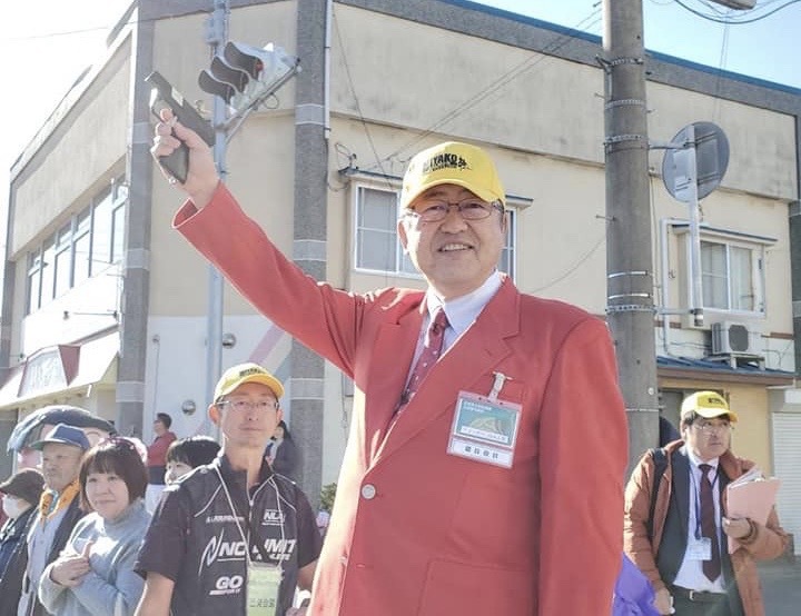 赤いジャケットを着て、スターターのピストルを上に掲げている市長の写真
