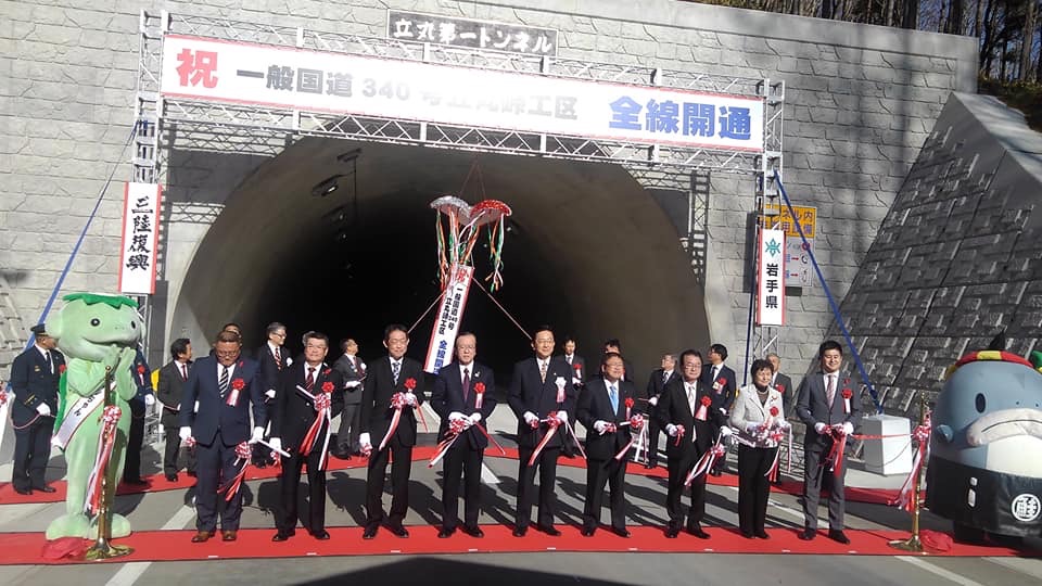 トンネルの前に敷かれたレッドカーペットの上に並びテープカットをする様子の市長や関係者の方たちの写真