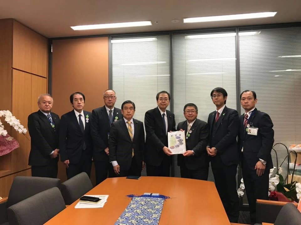 室内で要望書を一緒に持つ市長と男性と関係者の男性6名が横一列に並んでいる記念写真