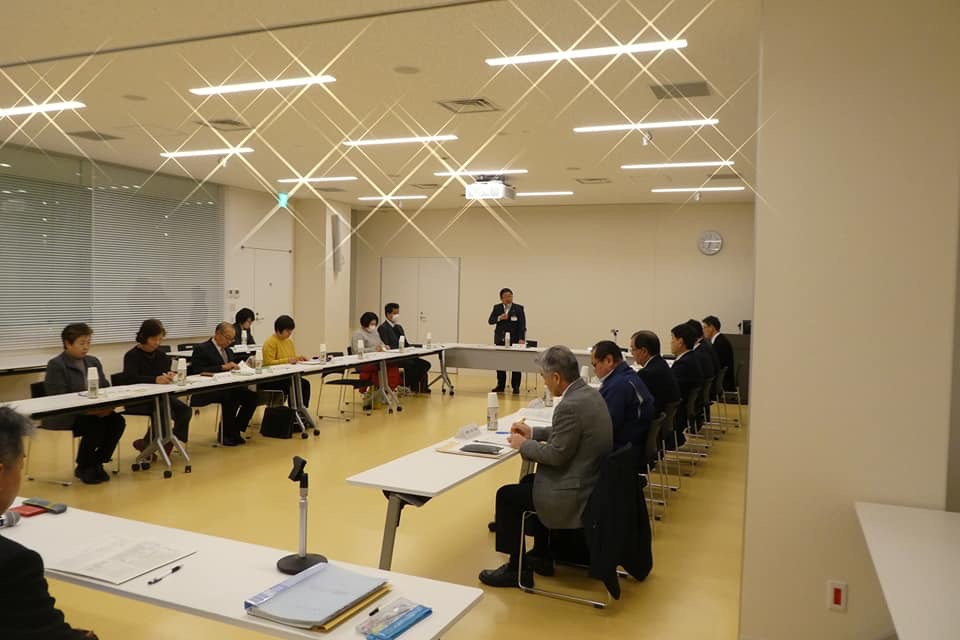 コの字型に並べられたテーブルの席に着く参加者の方々と立って話す市長の写真