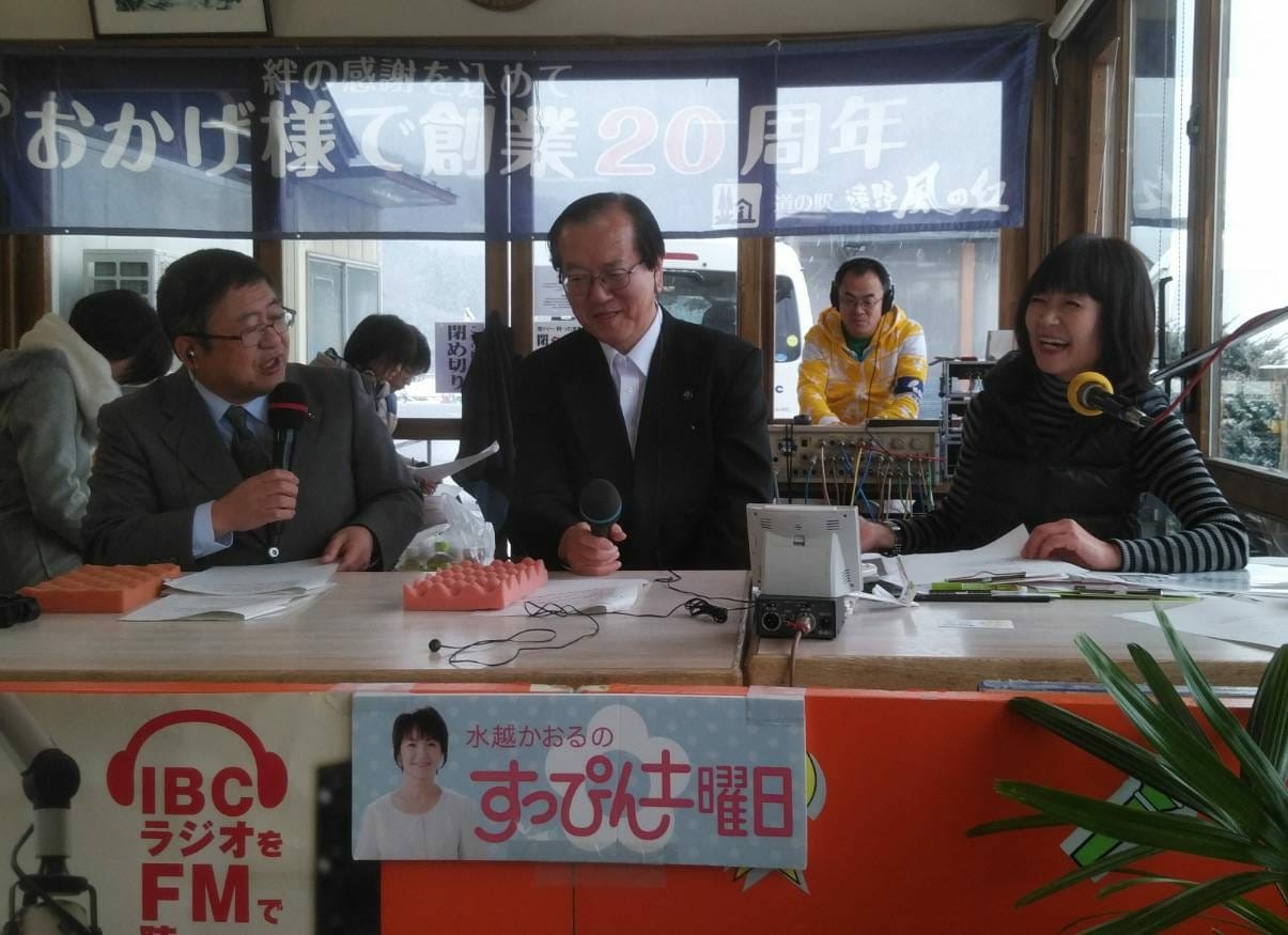 マイクを持ちラジオに出演する様子の山本市長と遠野市の本田敏秋市長、水越かおるアナウンサーを写した写真