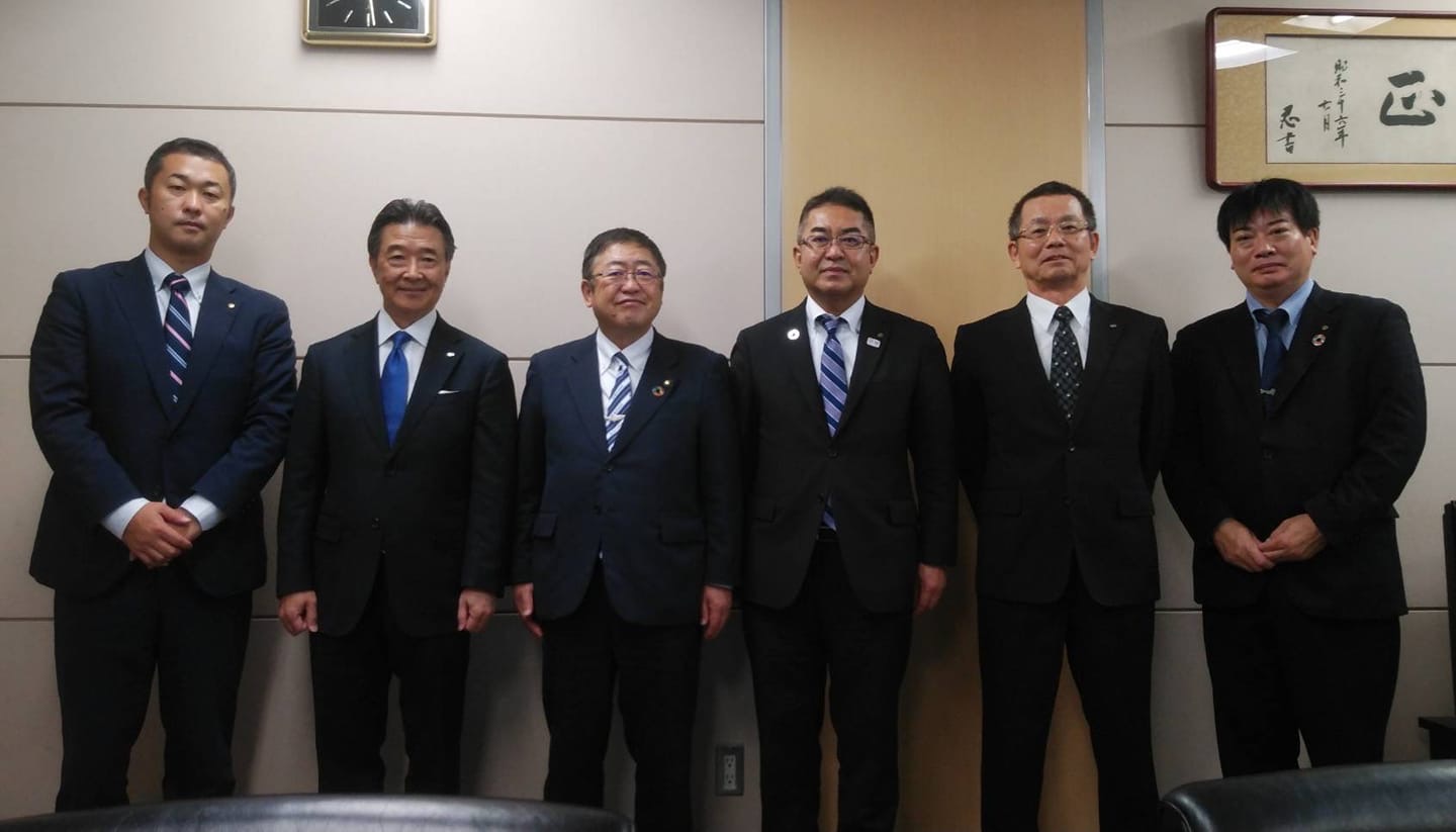 壁際に立って横一列に並ぶ市長と日清丸紅飼料株式会社の関係者の方々が写る記念写真