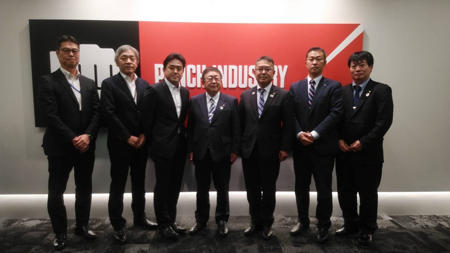 横一列に立って並ぶ市長とパンチ工業株式会社の関係者の方々が写る記念写真