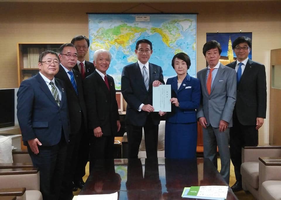 要望書を一緒に持つ岸田文雄政務調査会長と女性を中心に、市長を含む6名が両側に立つ記念写真