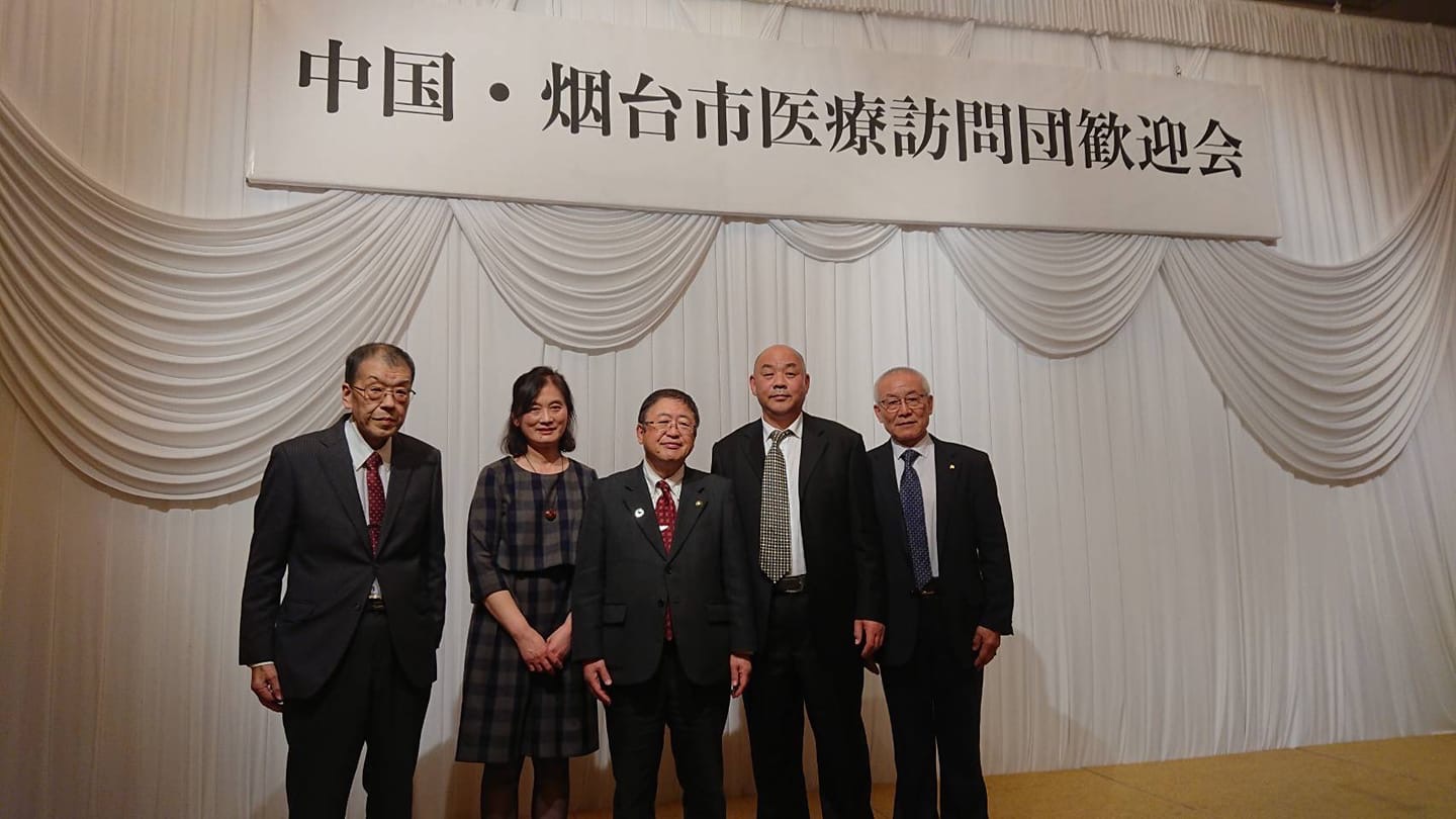 「中国・烟台市医療訪問団歓迎会」と書かれた横断幕が吊るされた会場で市長を中心に横一列に並ぶ宮古市と烟台市の関係者4名の記念写真