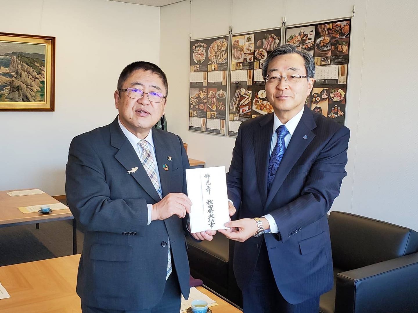 寄附金の封筒を正面に向けて一緒に持つ市長と佐藤芳彦副市長が記念撮影をしている写真