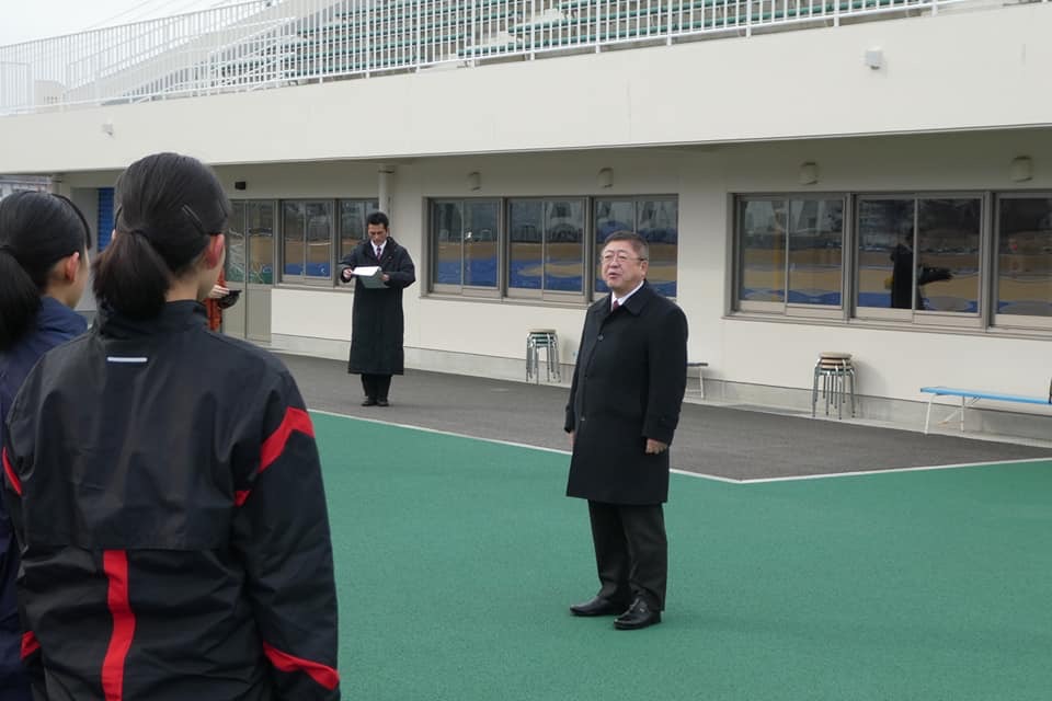 陸上競技場の屋外で、選手たちと向かい合って立つ市長が話をしている様子の写真