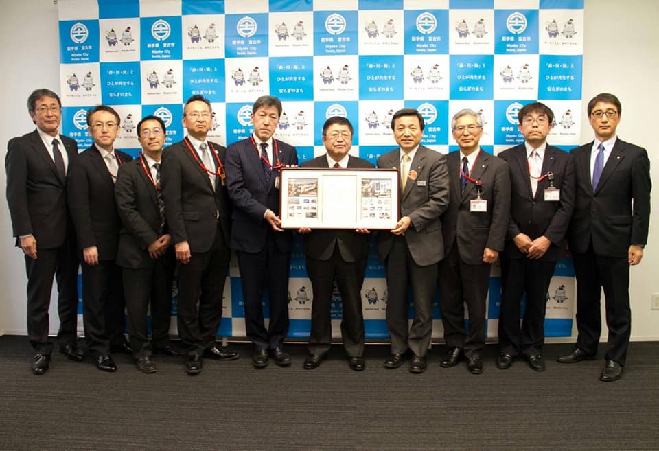 宮古市のバックパネルの前で、市長を挟んで中村一郎三陸鉄道社長と八重樫茂徳岩手県東部連絡会統括局長が額入りのフレーム切手を持ち、副市長や6名の関係者が横一列に並んでいる写真