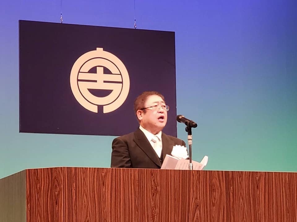 宮古市の市町村旗の前に置かれた演台で、式辞用紙を見ながら話をする市長の写真