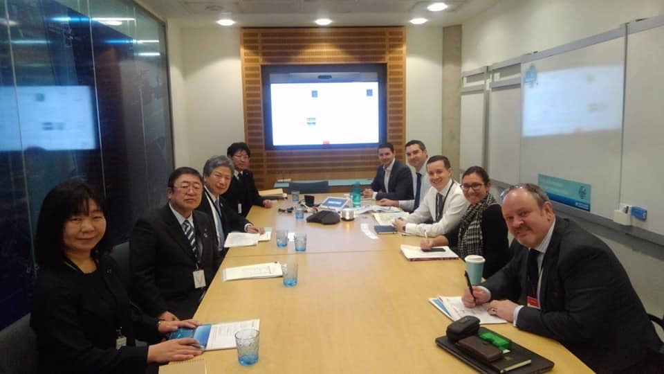 モニターの前に置かれたテーブルに向かい合うように座る市長や関係者の方々の記念写真