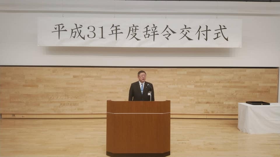 「平成31年度辞令交付式」と書かれた横断幕が吊るされた会場で、演台に置かれたマイクに向かい話をする様子の市長の写真