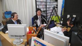 室蘭市の青山剛市長と共にヘッドフォンしてラジオ番組に出演し、インタビュアーと話をしている写真