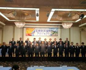 三陸防災復興プロジェクトと書かれた幕の下で、 参加者24人が2列に並び、右手でガッツポーズをして撮影した写真