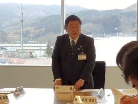 懇談会の中で市長と書かれたネームプレートの席で立ち、委員の皆さんにあいさつを述べている写真