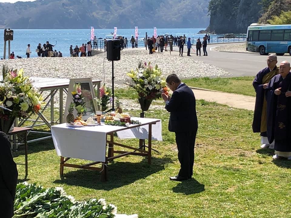花や供物が置かれた献花台に向かい少し頭を下げて合掌している様子の市長の写真