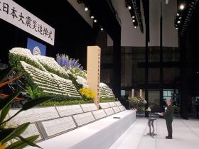 震災追悼式の大きな祭壇と祭壇の前に立つ市長を撮影した写真