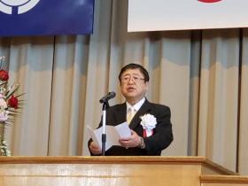 閉校式の会場で白の胸章をつけた市長が演台で、式辞を述べている写真