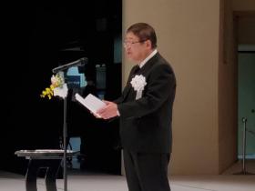 市長が白の胸章をつけて、追悼のことばをのべている写真