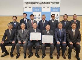 サインした協定書を日本郵便株式会社の方と市長がそれぞれ持ち、 関係者の方々13人が並んで撮影した写真
