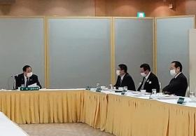 L字型に置かれたテーブルに座る4名の関係者を写した写真
