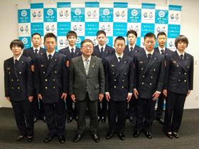 バックパネルの前で、2列に立って並ぶ市長と10名の制服姿の新規採用消防職員の方々の記念写真