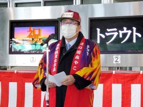 モニターが設置された市場で、法被と帽子を身に着けスタンドマイクに向かい話をする様子の市長の写真