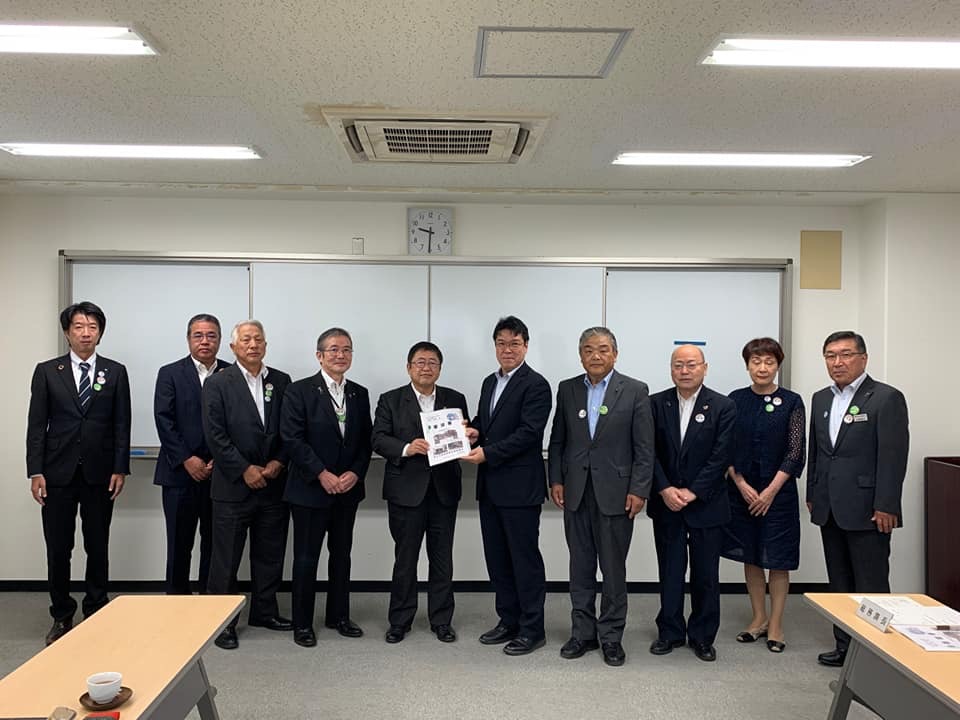 時計が掛けられた会議室内で、三陸国道事務所の代表の男性と市長が一緒に要望書を持ち他8名の関係者が横一列に並んでいる写真