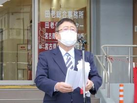 白い胸章を着け、式辞用紙を両手で持ちスタンドマイクに向かい話をする様子の市長の写真