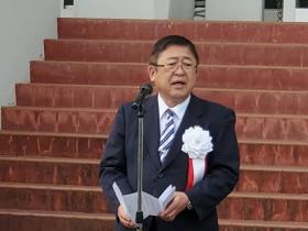階段の前に置かれたスタンドマイクに向かい話をする様子の市長の写真