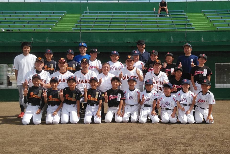 田老野球場で読売巨人軍OBの5名の講師と市長、小中学生の参加者や関係者が3列に並んでいる記念写真