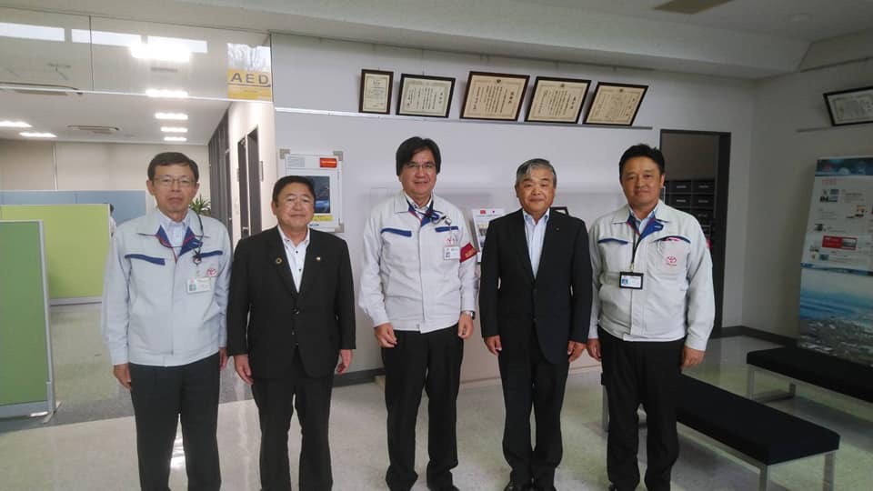 横一列に並ぶ市長とスーツを着た男性、グレーの作業用ジャケットを着たトヨタ自動車北海道株式会社の関係者の男性3名の記念写真