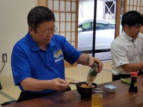 座敷の部屋で市長が青のポロシャツ姿で新名物の瓶ドンを器に入れている写真