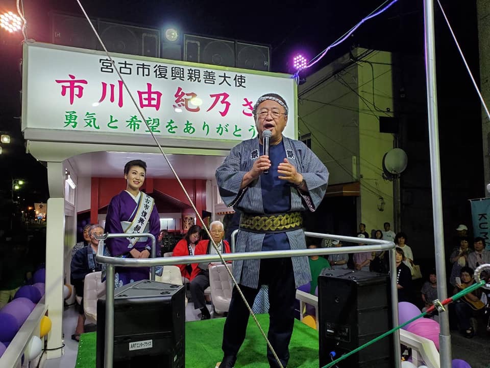 市川由紀乃号の上でマイクを手に歌う市長と、それを聞いている来場者や市川由紀乃さんの写真