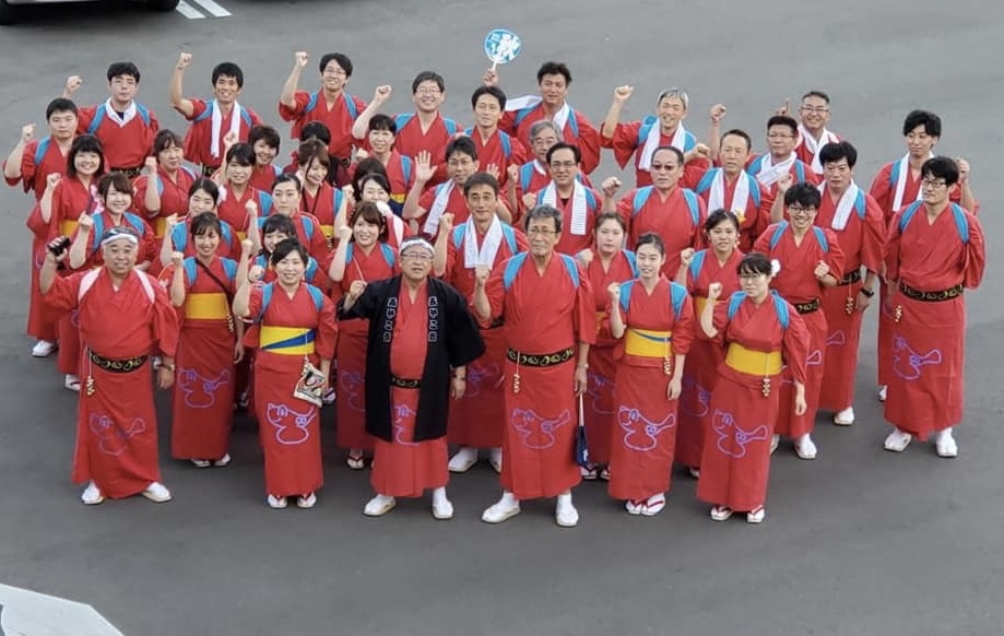 30名程の赤い着物を着た市役所チームの方々と市長がガッツポーズをしている集合写真