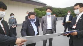 市長が藤原崇内閣府大臣政務官兼復興大臣政務官に職員が広げている地図を指さしながら、 復興の状況を説明している写真