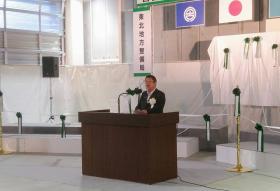市長が会場の演台で開通についてのあいさつを述べている写真
