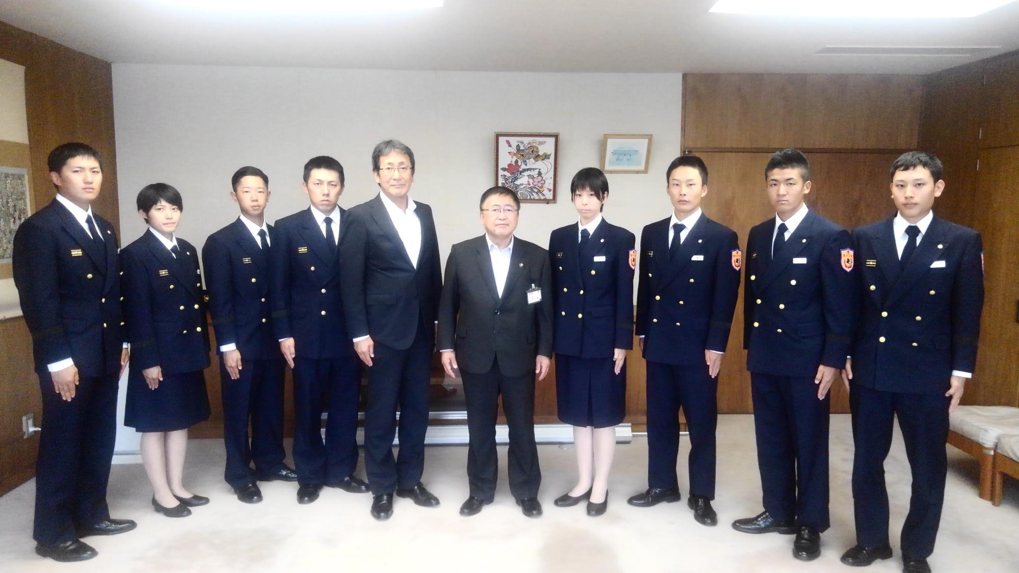 制服を着た新規採用の消防職員8名と市長、スーツを着た男性が横一列に並んでいる記念写真