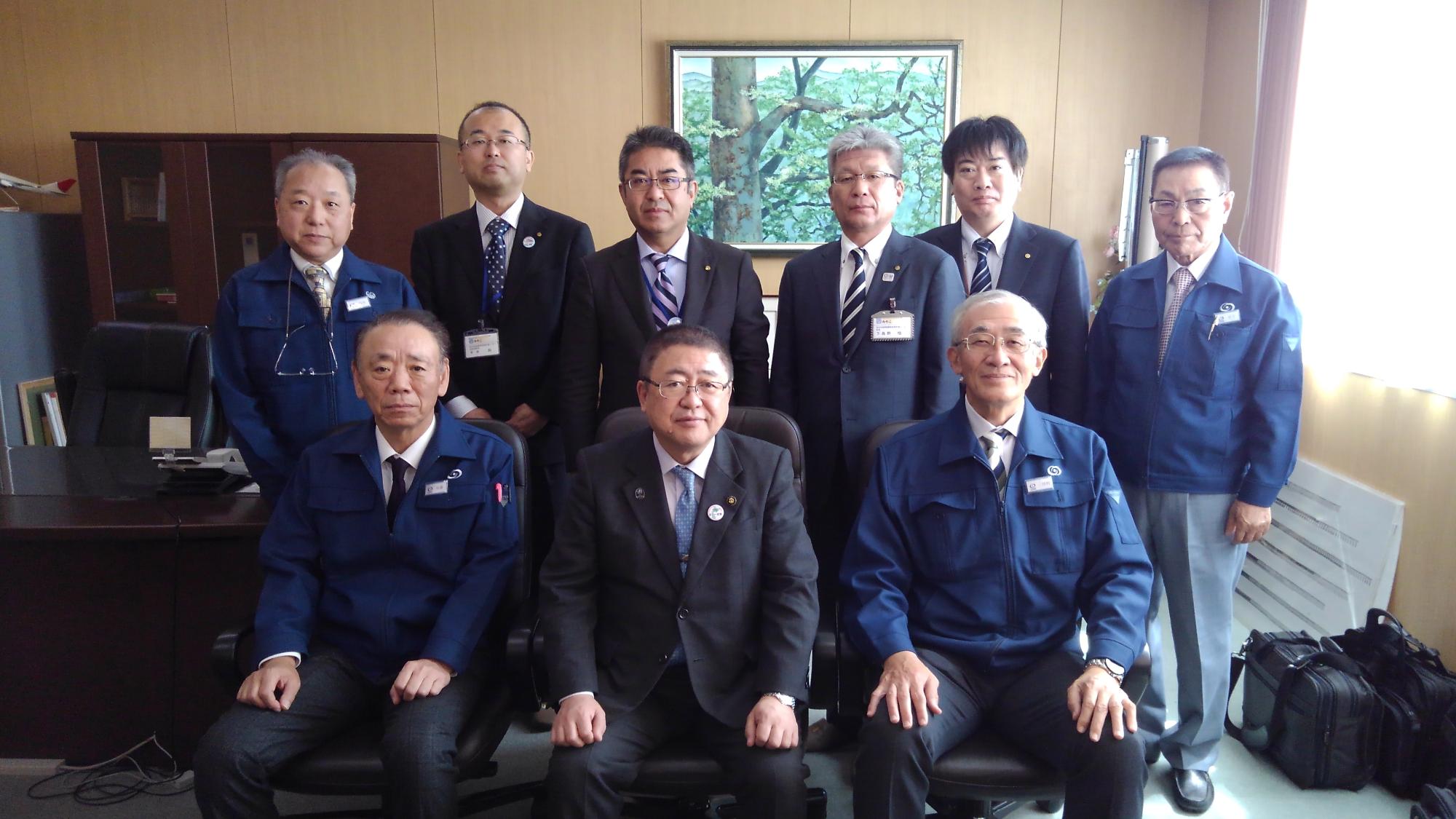 前列で椅子に座る市長と2名の男性、後列で立つ6名の男性が並んでいる記念写真