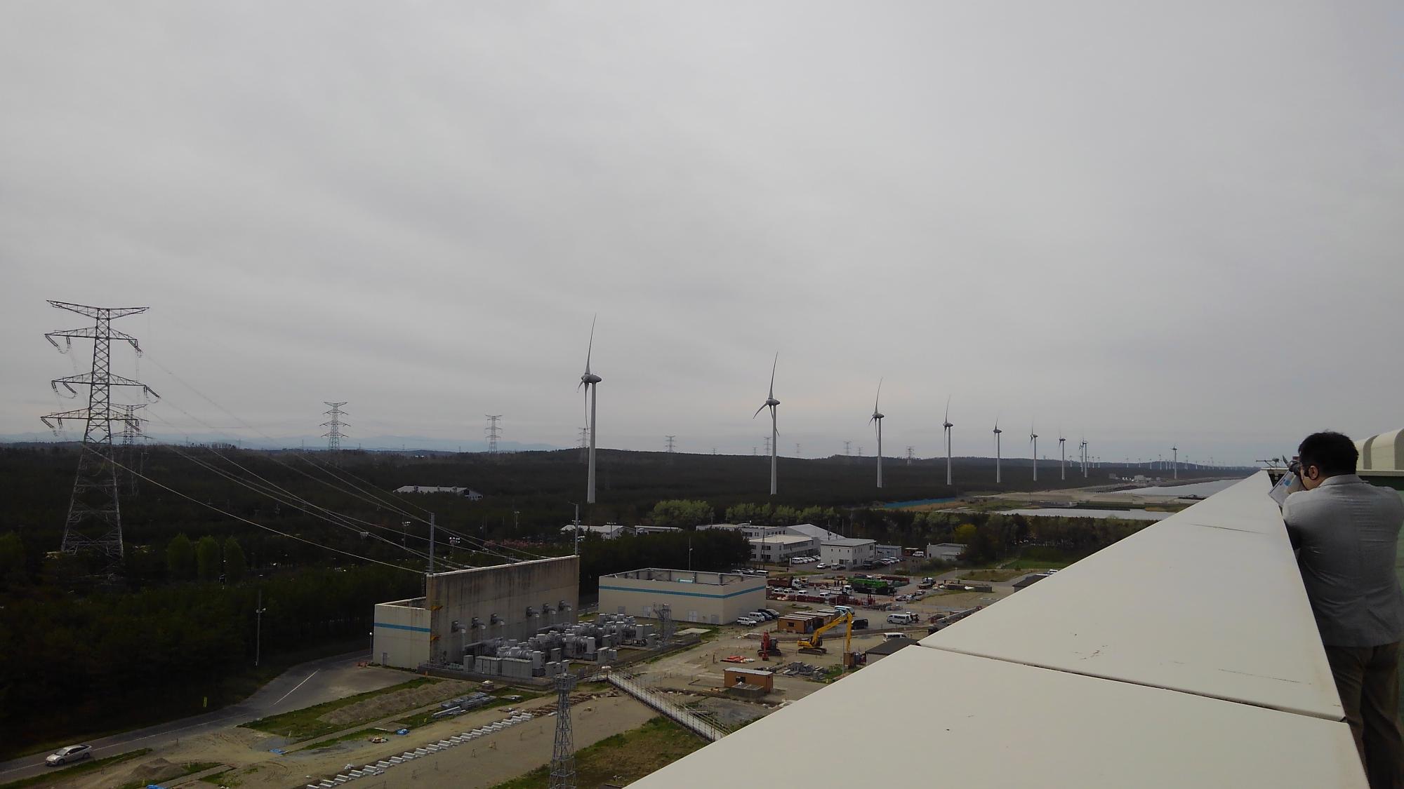 風力発電所の風車を建物の上から写した写真
