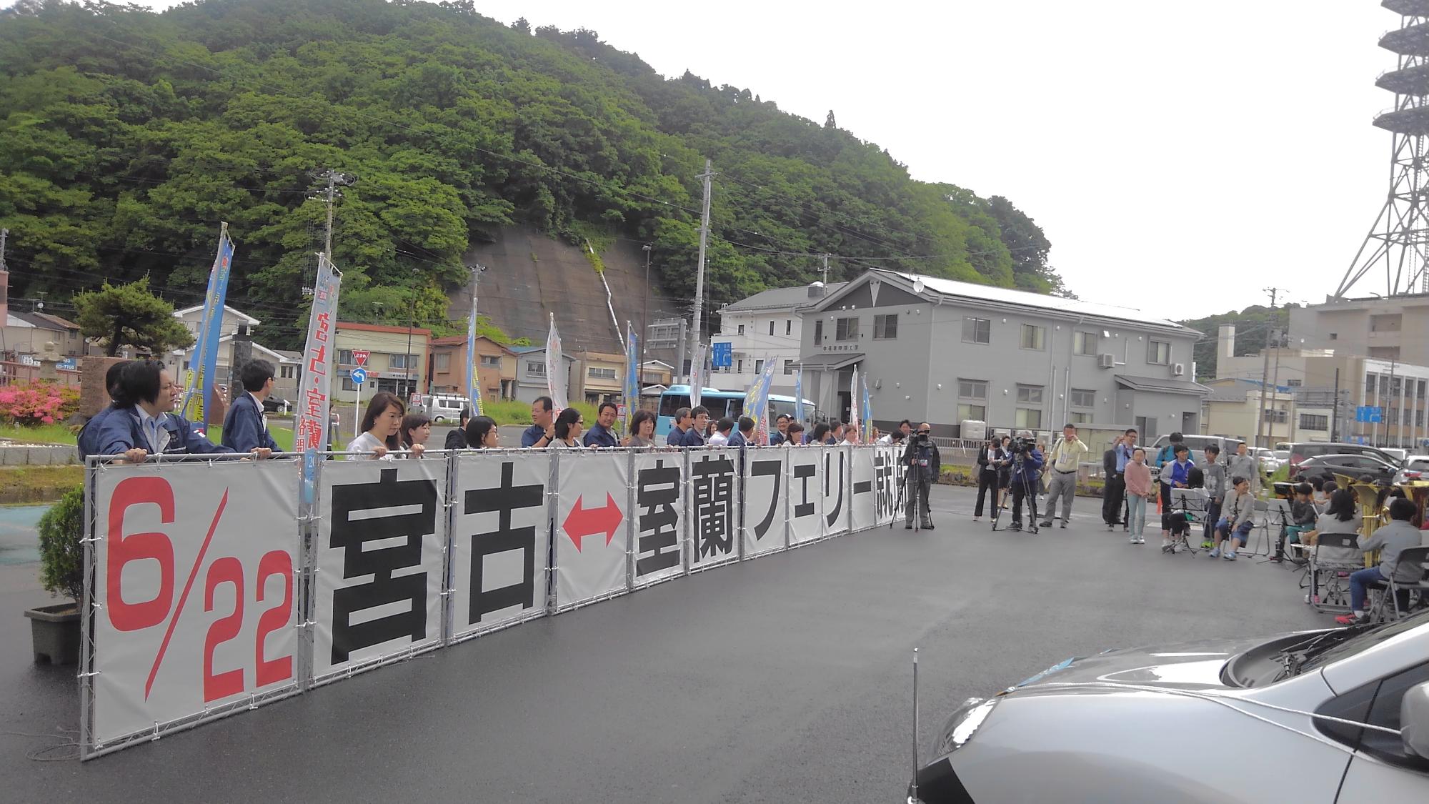 「6月22日 宮古↔室蘭フェリー就航」という看板を持った方たちが並んでいる写真