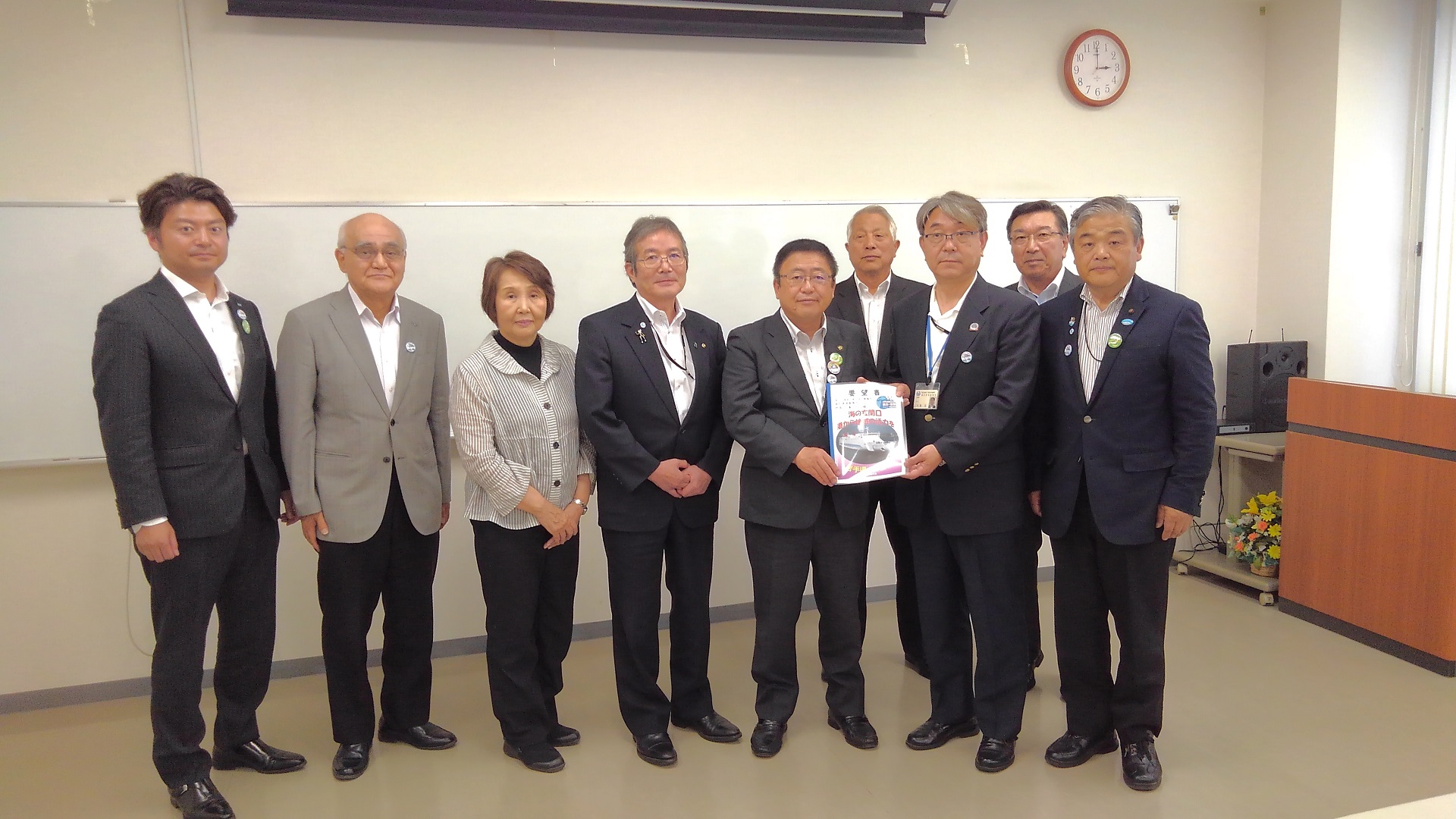 要望書を一緒に持つ市長と男性、関係者の男性6名と女性1名が横一列に並んでいる記念写真